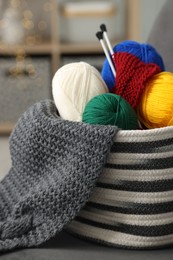 Skeins of soft yarn, knitting sample and needles on armchair indoors