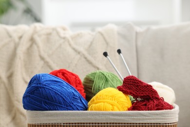 Skeins of soft yarn, knitting sample and needles in crate indoors