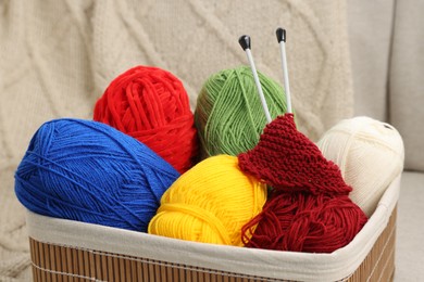 Skeins of soft yarn, knitting sample and needles in crate indoors