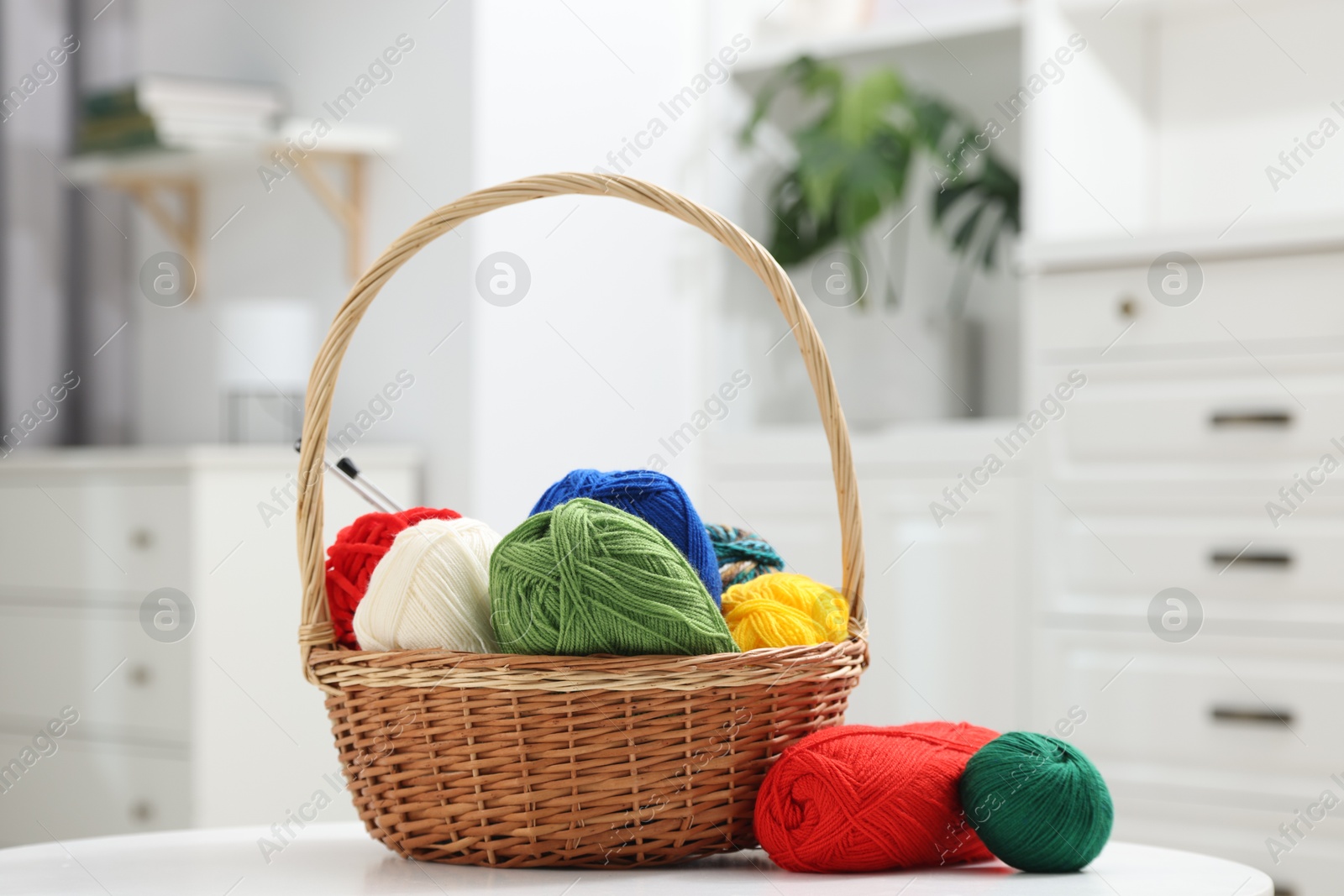 Photo of Skeins of soft yarn and knitting needles on white table indoors