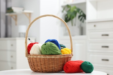 Skeins of soft yarn and knitting needles on white table indoors