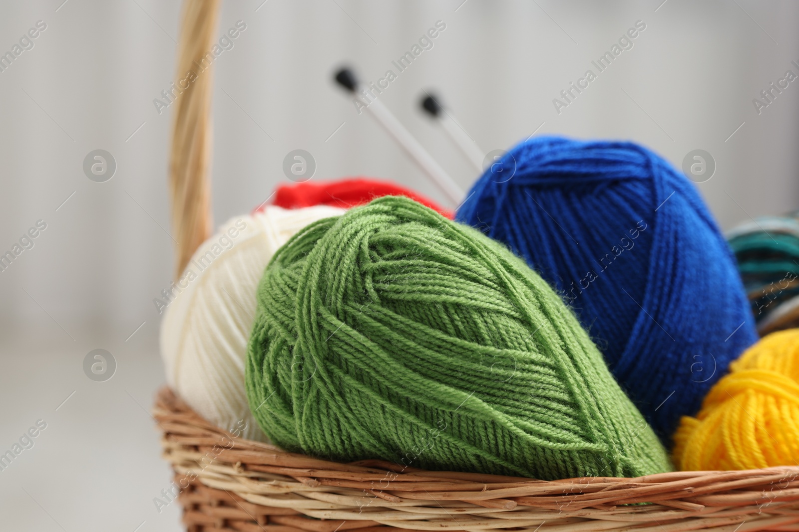 Photo of Knitting material. Skeins of soft yarn in wicker basket indoors, closeup