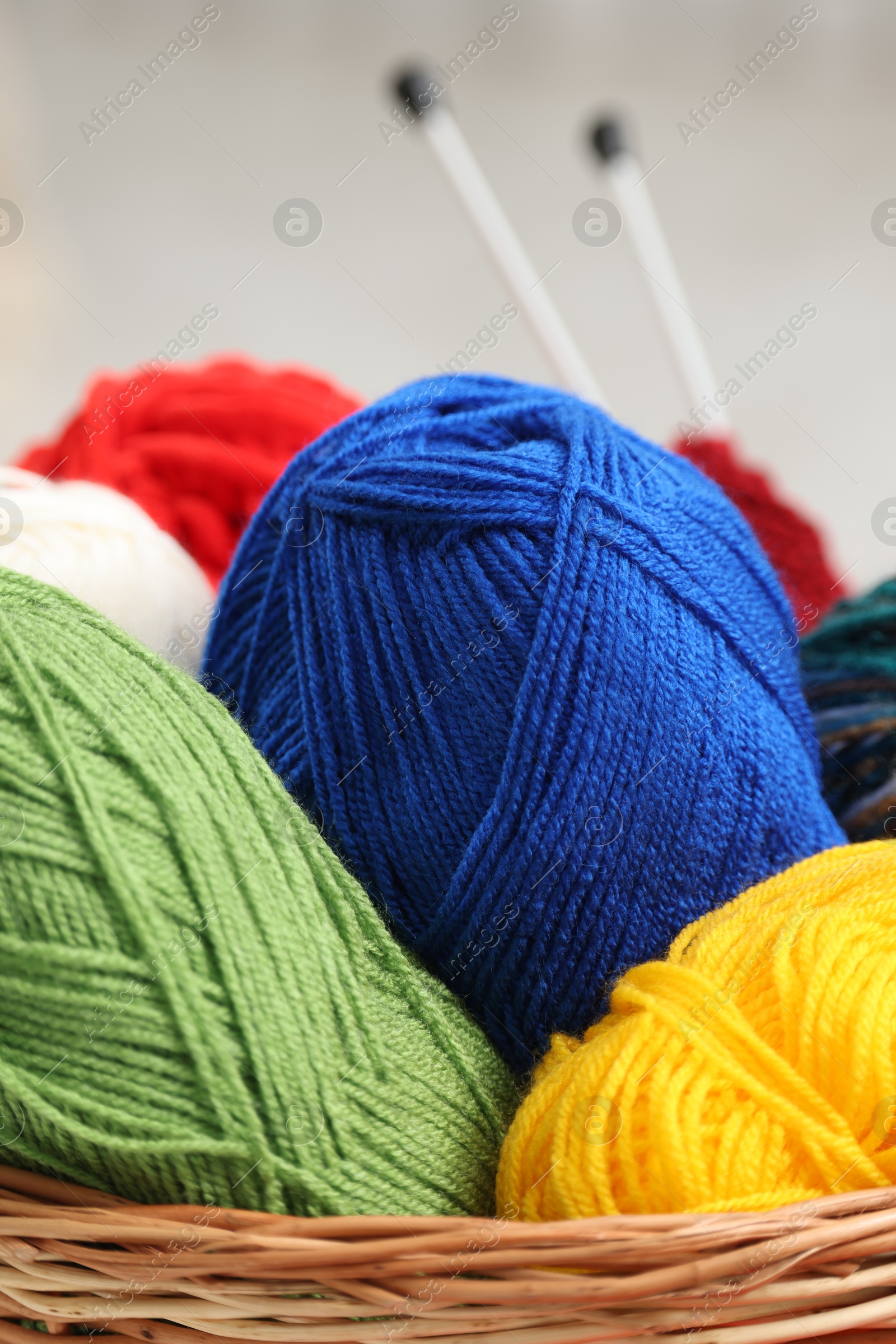 Photo of Knitting material. Skeins of soft yarn in wicker basket indoors, closeup