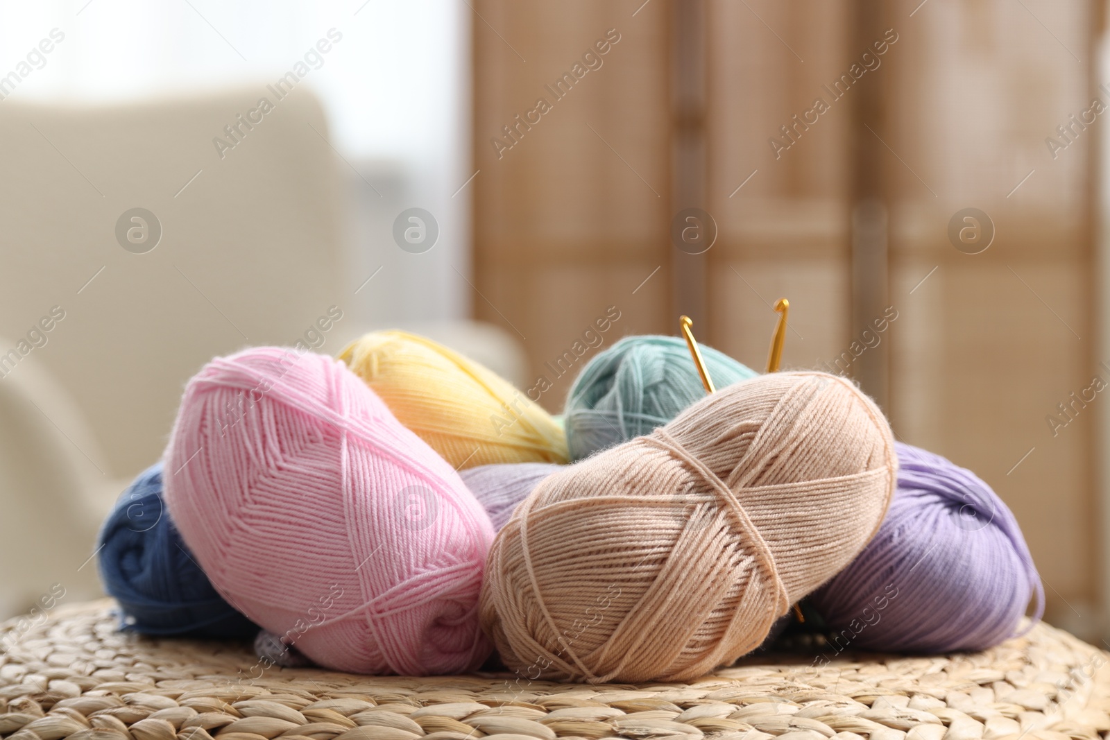 Photo of Knitting material. Skeins of soft yarn and crochet hooks on wicker surface indoors