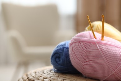 Knitting material. Skeins of soft yarn and crochet hooks on wicker surface indoors, closeup. Space for text