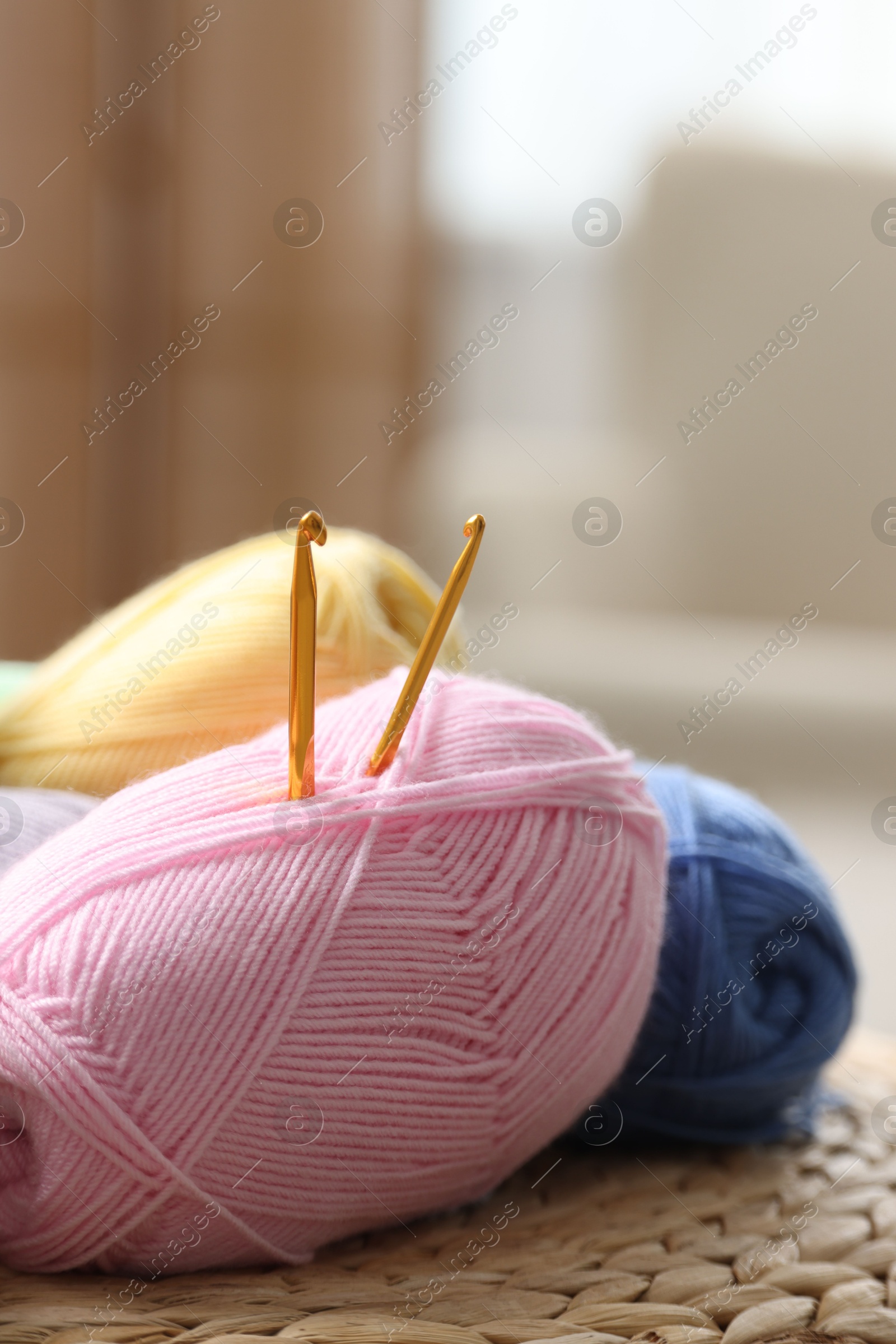 Photo of Knitting material. Skeins of soft yarn and crochet hooks on wicker surface indoors, closeup