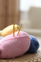 Photo of Knitting material. Skeins of soft yarn and crochet hooks on wicker surface indoors, closeup