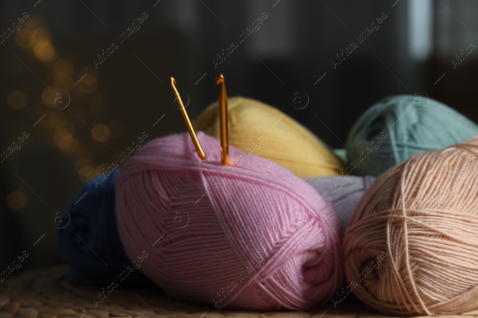 Photo of Knitting material. Skeins of soft yarn and crochet hooks on wicker surface indoors, closeup