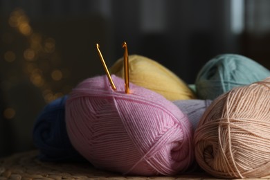 Photo of Knitting material. Skeins of soft yarn and crochet hooks on wicker surface indoors, closeup