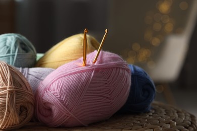 Knitting material. Skeins of soft yarn and crochet hooks on wicker surface indoors, closeup