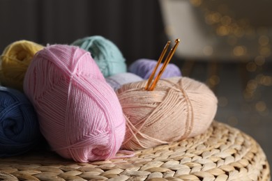 Photo of Knitting material. Skeins of soft yarn and crochet hooks on wicker surface indoors, closeup