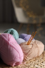 Photo of Knitting material. Skeins of soft yarn and crochet hooks on wicker surface indoors, closeup