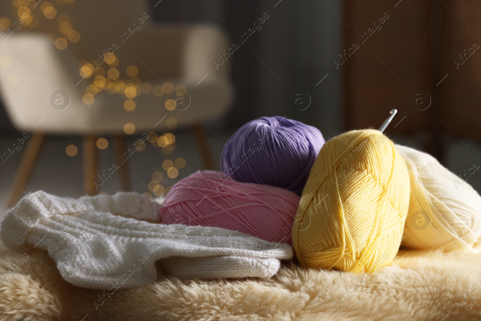 Photo of Knitting material. Skeins of yarn, crochet hook and socks on soft surface indoors