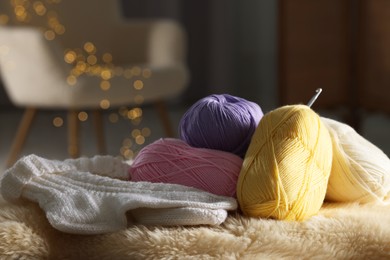 Knitting material. Skeins of yarn, crochet hook and socks on soft surface indoors