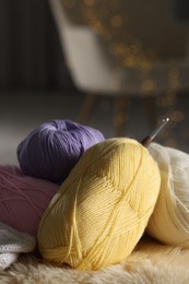 Knitting material. Skeins of yarn and crochet hook on soft surface indoors, closeup