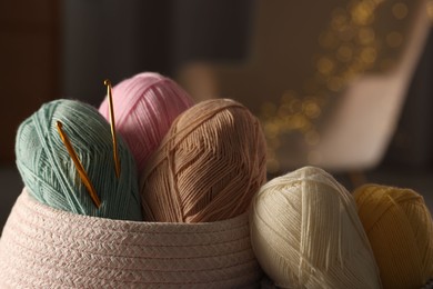 Photo of Knitting material. Skeins of soft yarn and crochet hooks against blurred background, closeup