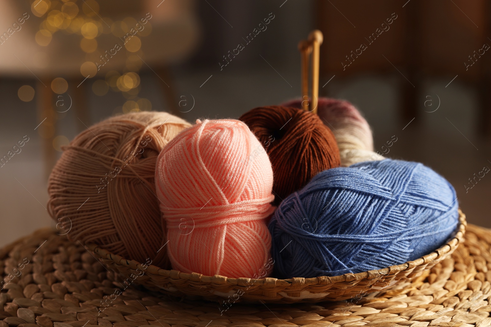 Photo of Knitting material. Skeins of soft yarn in wicker bowl on table, closeup