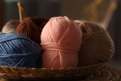 Photo of Knitting material. Skeins of soft yarn in wicker bowl on table, closeup