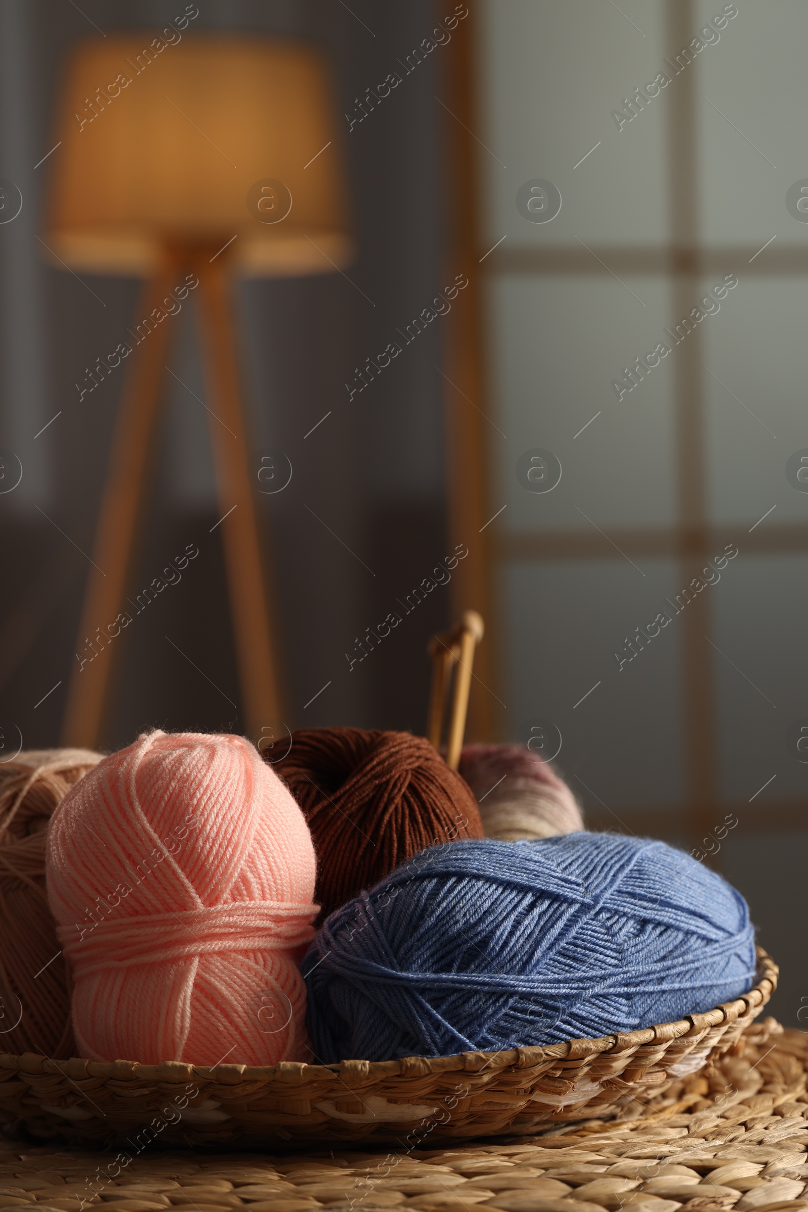 Photo of Knitting material. Skeins of soft yarn in wicker bowl on table indoors