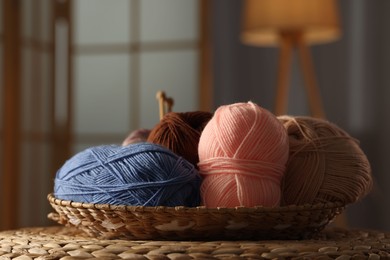 Knitting material. Skeins of soft yarn in wicker bowl on table indoors, closeup