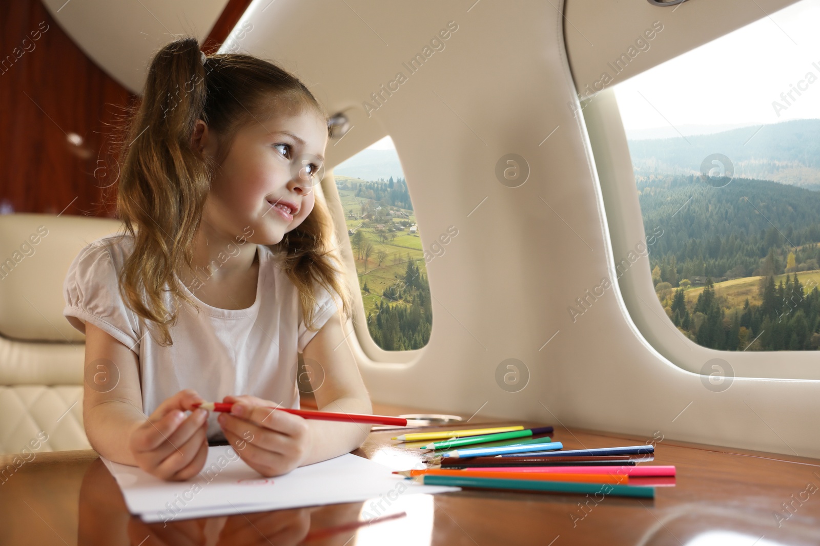 Image of Little girl looking at mountains from airplane window