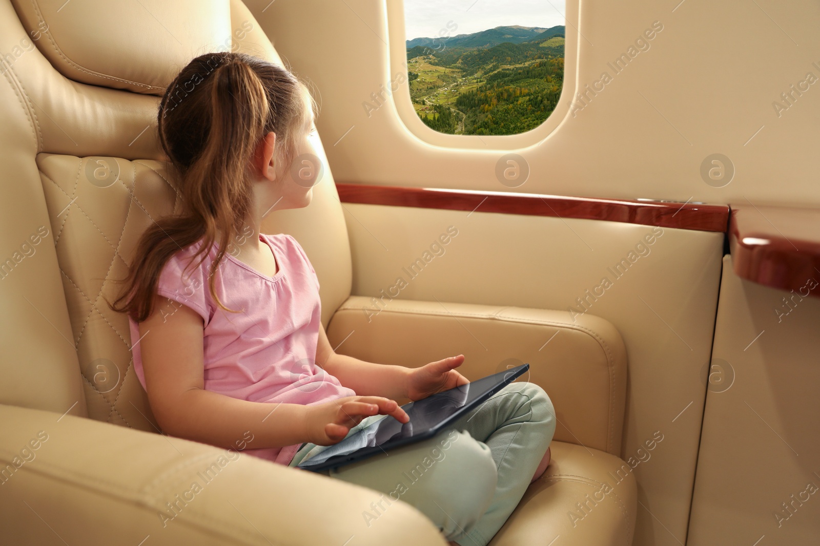 Image of Little girl looking at mountains from airplane window