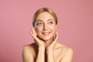 Portrait of smiling woman with healthy skin on pink background