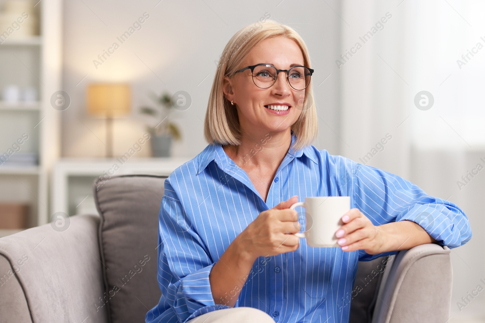 Photo of Smiling middle aged woman with cup of hot drink at home