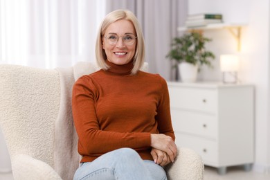 Portrait of smiling middle aged woman on armchair at home