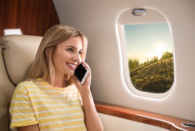 Woman talking on phone in cabin while airplane taking off or landing, view on mountains from window