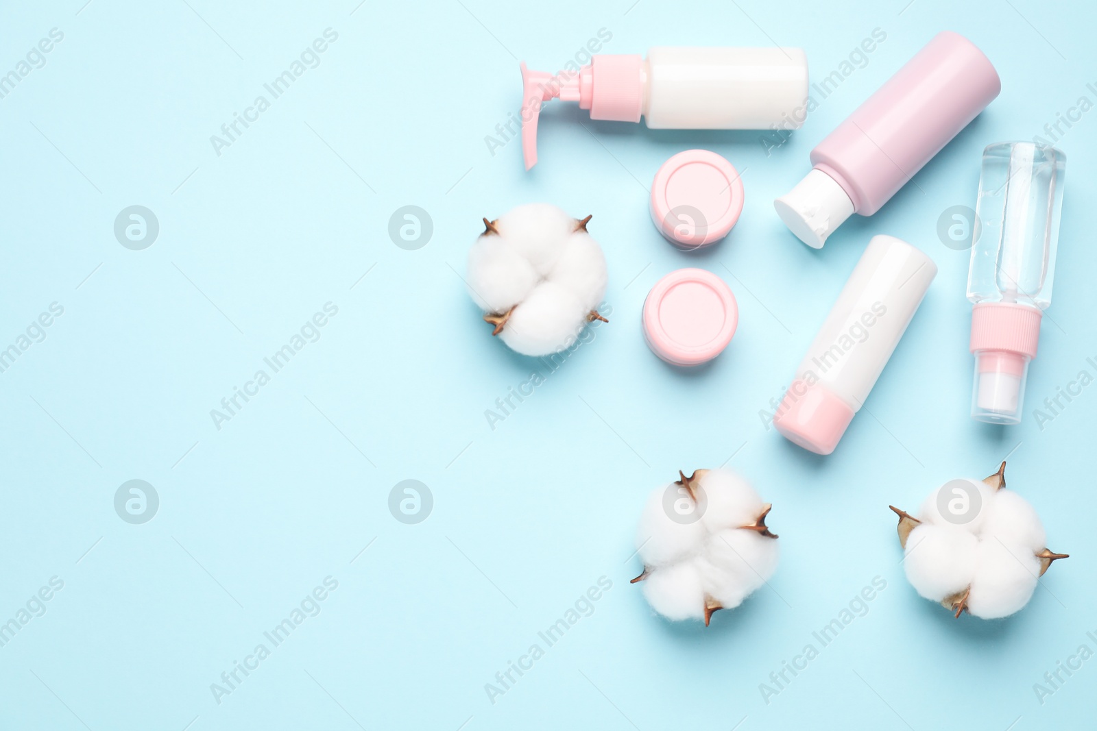 Photo of Different cosmetic products and cotton flowers on light blue background, flat lay. Space for text