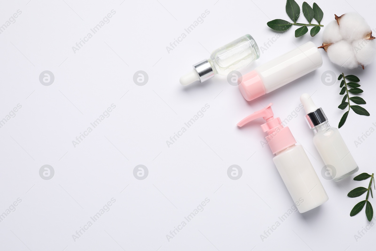 Photo of Different cosmetic products, cotton flower and leaves on white background, flat lay. Space for text