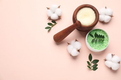 Photo of Different cosmetic products, cotton flowers and green leaves on beige background, flat lay. Space for text