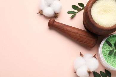 Photo of Different cosmetic products, cotton flowers and green leaves on beige background, flat lay. Space for text