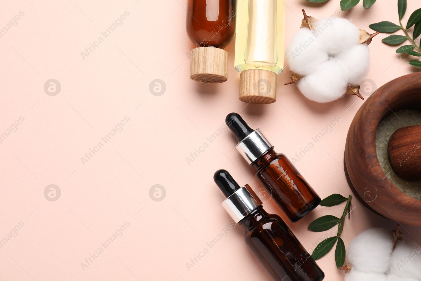 Photo of Different cosmetic products, cotton flowers and green leaves on beige background, flat lay. Space for text