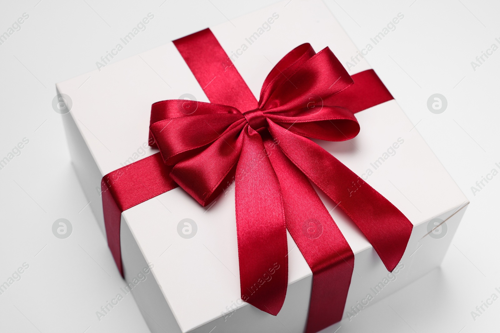 Photo of Gift box with red bow on light grey background, closeup