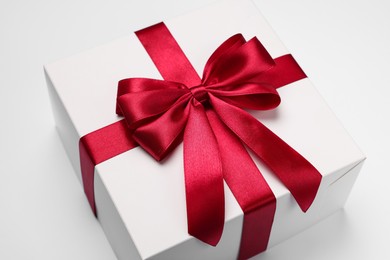 Photo of Gift box with red bow on light grey background, closeup