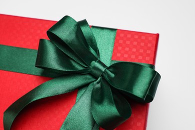 Gift box with green bow on light grey background, closeup