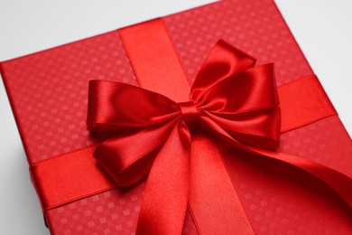 Gift box with bow on light grey background, closeup