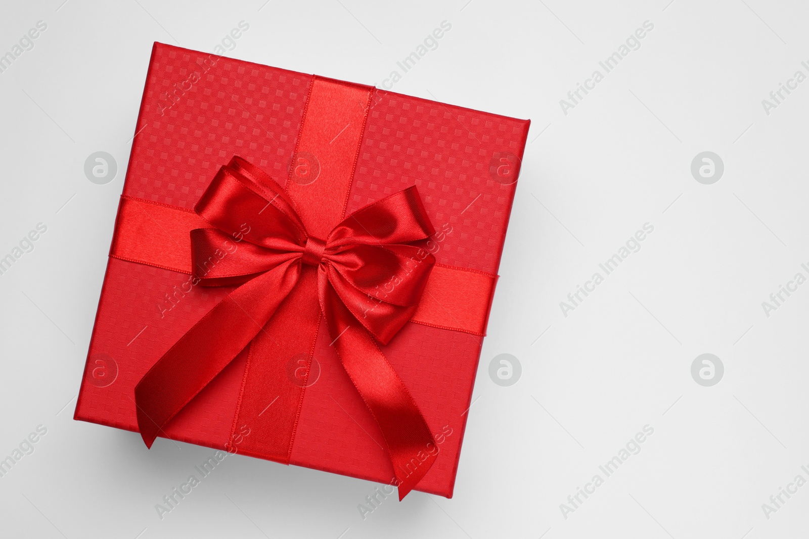 Photo of Gift box with bow on light grey background, top view. Space for text