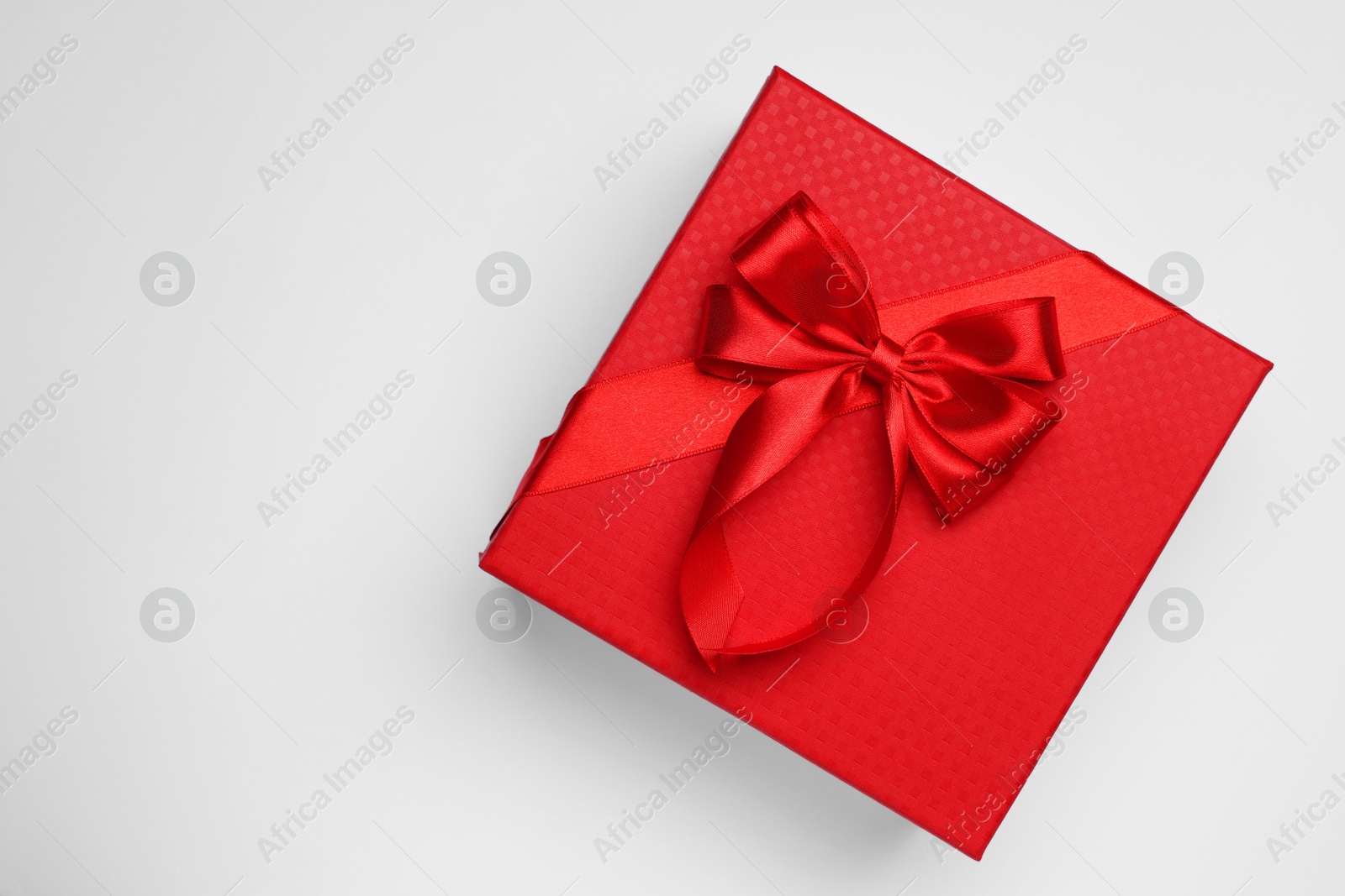 Photo of Gift box with bow on light grey background, top view. Space for text