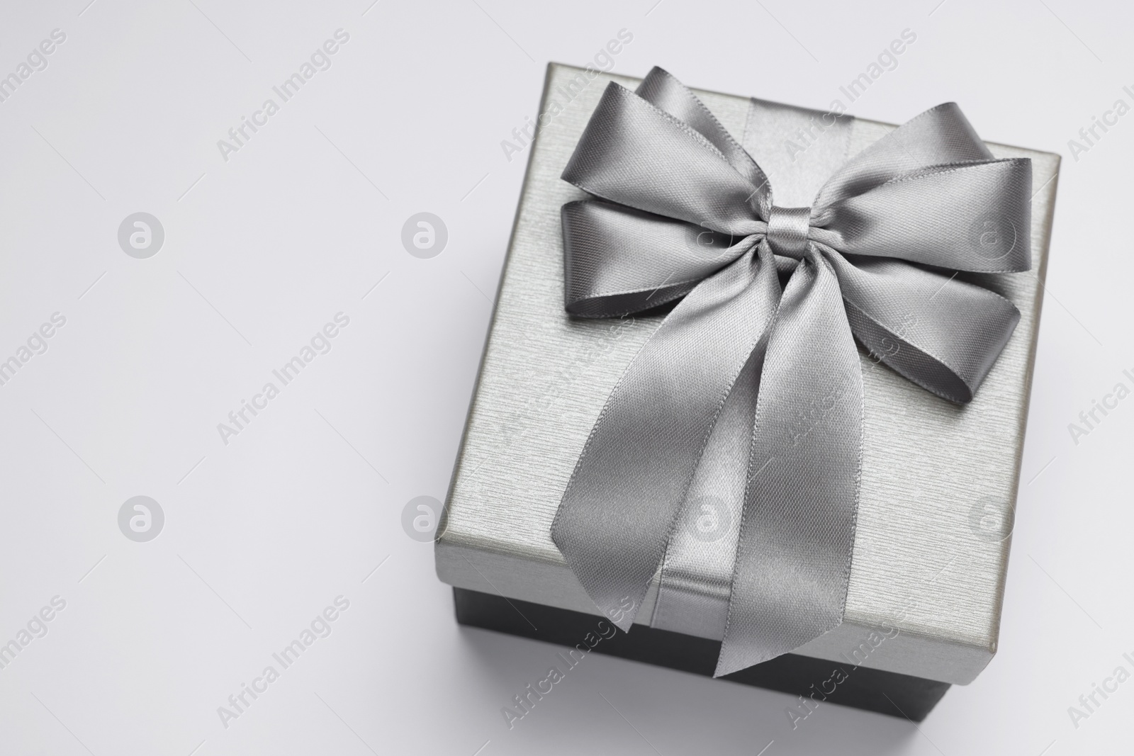 Photo of Gift box with bow on light grey background, above view. Space for text