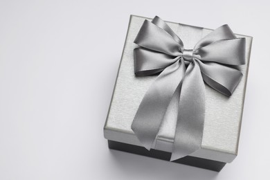 Photo of Gift box with bow on light grey background, above view. Space for text