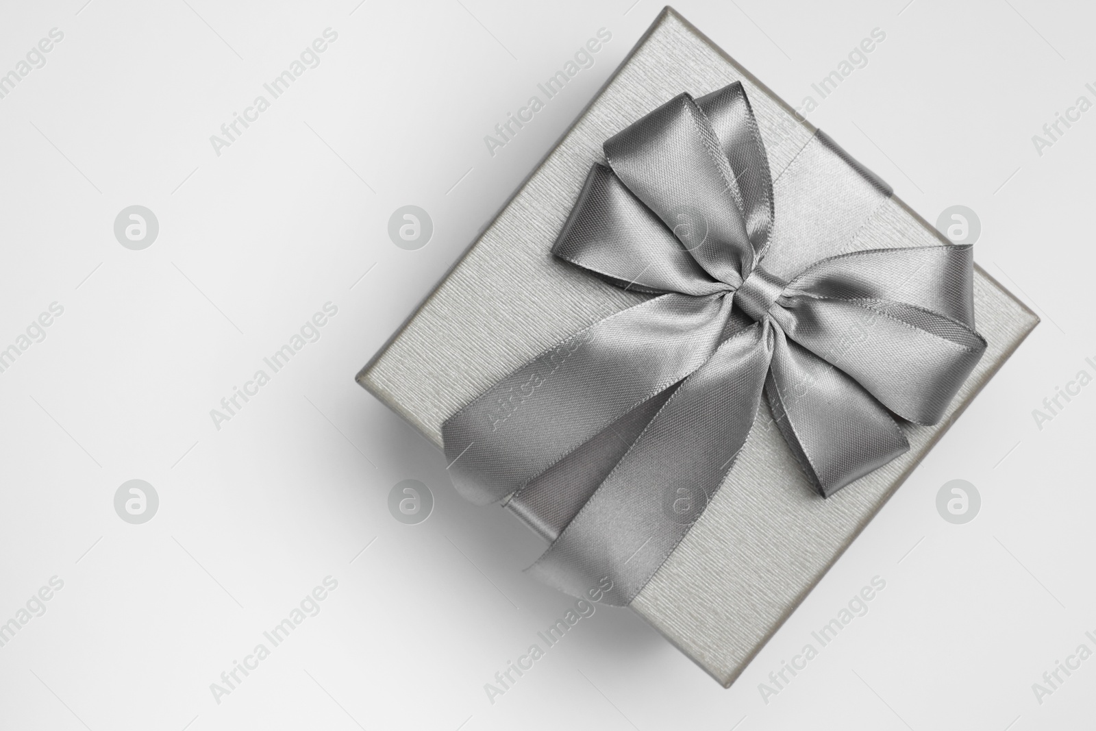 Photo of Gift box with bow on light grey background, top view. Space for text