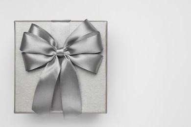 Photo of Gift box with bow on light grey background, top view. Space for text