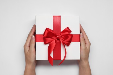 Photo of Woman holding gift box with bow on white background, top view