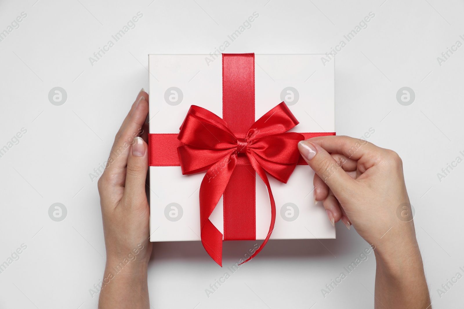 Photo of Woman holding gift box with bow on white background, top view