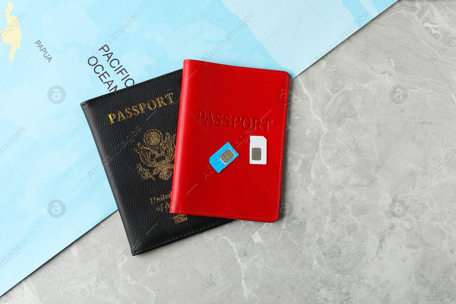 Photo of Passports, SIM cards and world map on grey marble table, flat lay