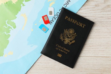 Photo of Passport, SIM cards and world map on wooden table, flat lay