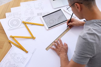 Architect making engineering drawing at wooden table in office, above view